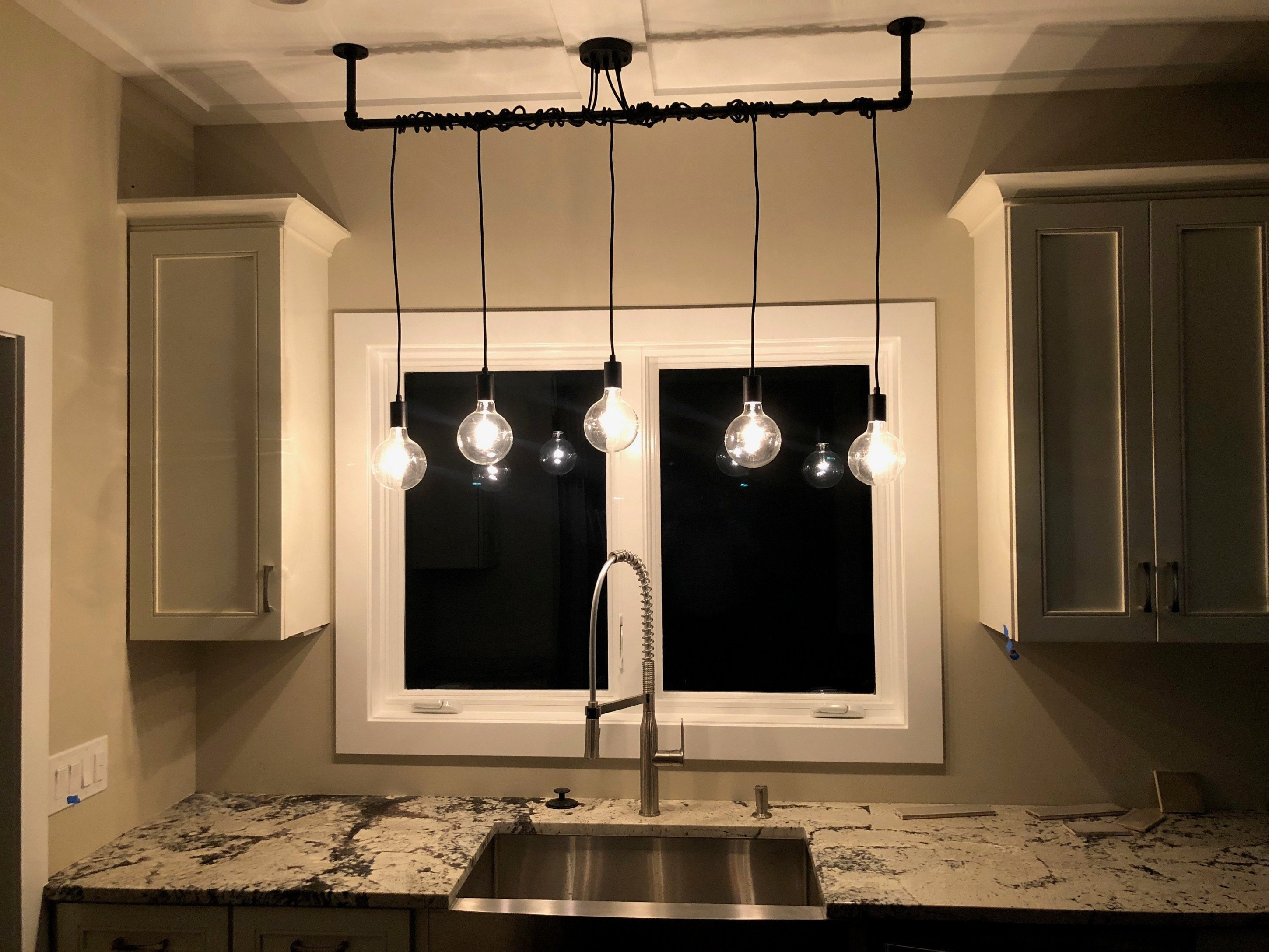 drum pendant lighting over kitchen sink with window
