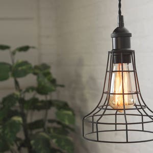 May include: A black caged pendant light with a clear glass bulb. The light is hanging from a white ceiling.