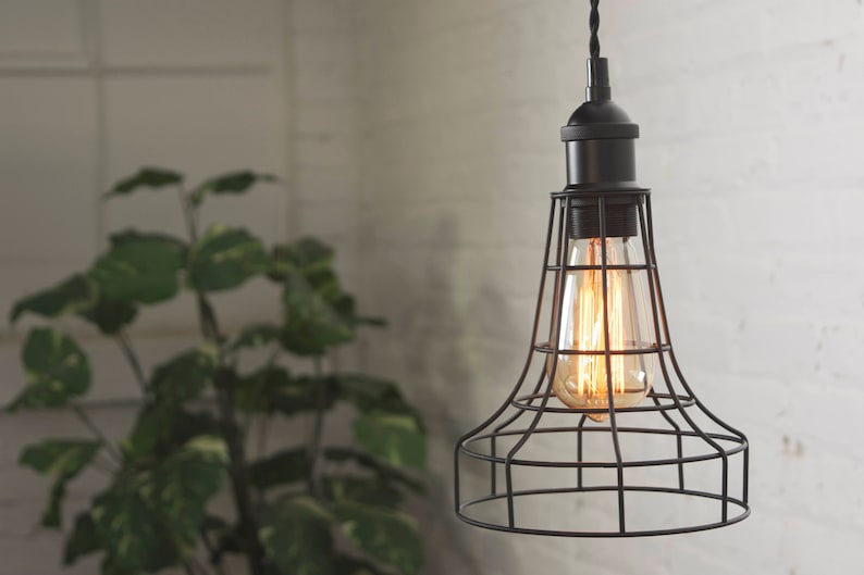 May include: A black caged pendant light with a clear glass bulb. The light is hanging from a white ceiling.