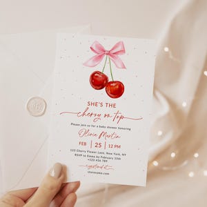 May include: A pink and red baby shower invitation featuring a cherry on top design. The invitation reads "She's the cherry on top" and includes the name Olivia Martin, the date 25th February, and the time 12 PM. The invitation also includes the address 123 Cherry Flower Lane, New York, NY and the RSVP information.