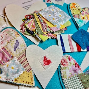 May include: A craft kit for making patchwork heart ornaments. The kit includes a variety of colorful fabric scraps, embroidery floss, and instructions. The kit also includes a white cardstock heart with a red bird design.