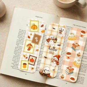 Könnte beinhalten: Drei rechteckige Lesezeichen mit herbstlichen Motiven. Das erste zeigt Briefmarkendesigns mit Kürbissen und Pilzen. Das zweite enthält Geister, Karomuster und den Text hello FALL. Das dritte zeigt Zimtschnecken und Bücherstapel.