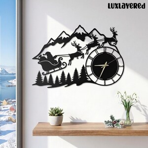 May include: A black wall clock featuring a silhouette of Santa in a sleigh pulled by reindeer over a forest and mountain range. The clock face is circular with thin black lines for numbers and gold hands. The text LUXLAYERED is at the top.