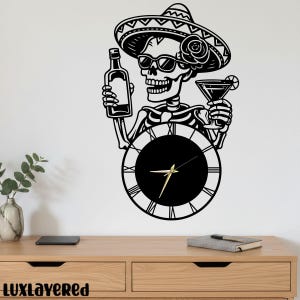May include: Black and white wall clock featuring a skeleton wearing a sombrero and sunglasses, holding a bottle and a cocktail. The clock has a black face with gold hands and Roman numerals. The clock is mounted on a white wall.