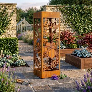 May include: A tall, rectangular, rust-colored metal garden sculpture featuring intricate laser-cut designs of a drum set, musical notes, and swirling staff lines. The hollow, open-frame structure stands upright on a stone patio surface.