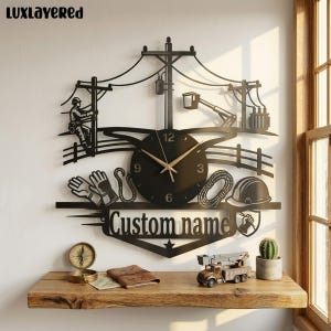 May include: A black metal wall clock featuring a silhouette design of a utility worker on a pole, a bucket truck, power lines, gloves, a rope, and a hard hat. The clock face has gold hands and the text Custom name in a cutout style.