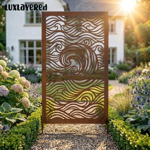May include: A rectangular metal privacy screen featuring a laser-cut pattern of swirling ocean waves. The panel has a rusted brown finish and is positioned upright on a gravel path. The text LUXLAYERED is visible in the top left corner.