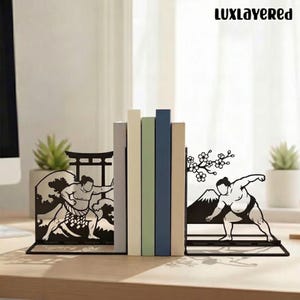 May include: Black metal bookends featuring sumo wrestlers. One bookend depicts a wrestler with a wave and a traditional Japanese gate. The other shows a wrestler with Mount Fuji and cherry blossoms. The text "LUXLayered" is at the top.
