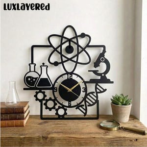 May include: Black metal wall clock with a science theme. The clock features a circular face with gold hands, surrounded by atom, microscope, DNA, and beaker designs. The text "LUXLAYERED" is at the top.