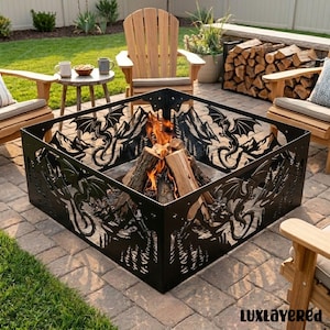 May include: A black, square fire pit with dragon and mountain cutouts. The fire pit is filled with burning wood. The scene is set outdoors with wooden chairs and a small table. The text "Luxlayered" is in the bottom right corner.