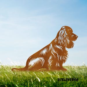 May include: A brown metal silhouette of a Cocker Spaniel dog sitting in a grassy field under a blue sky. The dog's fur is detailed with cut-out lines. The text "luxlayered" is at the bottom right.