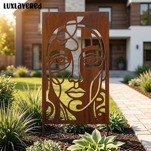 May include: A rectangular metal garden screen with a rust-coloured finish featuring a laser-cut abstract face design. The panel displays intricate, flowing lines forming eyes, a nose, and lips, with the text LUXLAYERED visible in the top left corner.