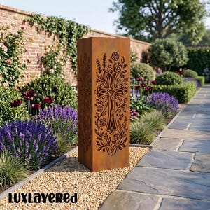 May include: A weathered metal garden pillar, rectangular in shape, featuring a cut-out cross design with floral and vine patterns. The pillar stands in a garden with lavender and a stone path. The text "luxlayered" is visible at the bottom.