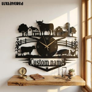 May include: A black metal wall clock featuring a farm scene with a bull, a cow, a pig, a chicken, a barn, a house, and a fence. The clock face has gold hands and the text "Custom name" is displayed at the bottom. The brand name "LUXLAYERED" is in the top left corner.