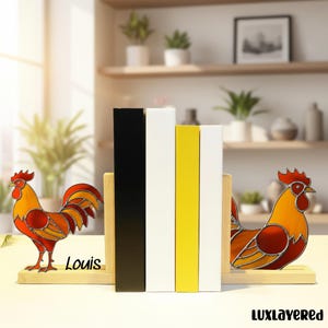 May include: Decorative rooster bookends with a stained glass design in shades of red, orange, and yellow. The bookends are made of wood and feature the name "Louis". The image also shows black, white, and yellow bookends.