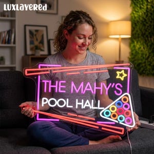 May include: A neon sign with the text "THE MAHY'S POOL HALL" in pink and white. The sign has a rectangular shape with a star and a triangle of pool balls. The sign is outlined in pink and orange neon.