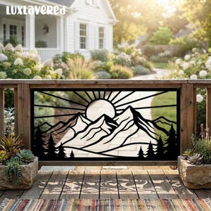 May include: A black metal decorative panel featuring a laser-cut design of a sun rising over a mountain range with pine trees in the foreground. The rectangular panel is mounted within a wooden railing on a deck, displaying a landscape scene.