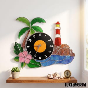 Könnte beinhalten: Eine Wanduhr mit einem Buntglasdesign, das eine grüne Palme, eine rosa Hibiskusblüte und einen rot-weißen Leuchtturm an einer felsigen Küste zeigt. Das Zifferblatt ist ein schwarzer Kreis mit gelber Mitte und weißen Zahlen von 1 bis 12.