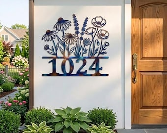 May include: A metal address sign with a floral design and the number 1024. The sign is mounted on a white wall next to a wooden door. The sign features a variety of flowers in a blue and brown color scheme.