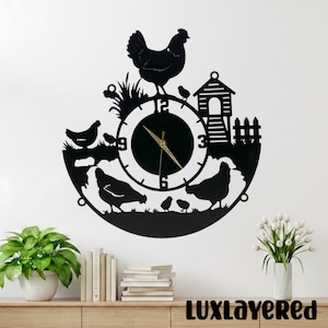 May include: Black metal wall clock featuring a hen, chicks, and a rooster. The clock face has gold hands and black numbers. The clock has a farm theme with a chicken coop and fence design. The text "LUXLAYERED" is at the bottom.