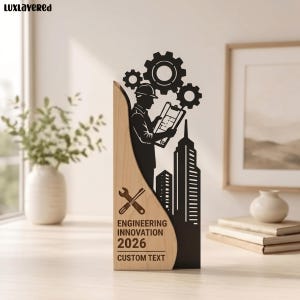 Puede incluir: Una placa de premio vertical con un panel de madera clara a la izquierda y una silueta negra recortada a la derecha. El diseño muestra a un ingeniero con un plano, engranajes y un horizonte urbano. El texto dice ENGINEERING INNOVATION 2026 CUSTOM TEXT.