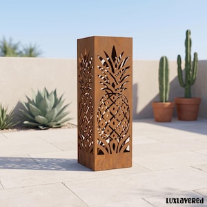 May include: A tall, rectangular, rust-coloured metal garden sculpture featuring laser-cut pineapple motifs on its sides. The structure has a weathered, oxidised finish and an open-work design that allows light to pass through the pineapple patterns.