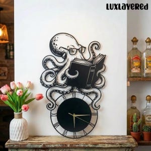 Op de afbeelding: Een zwarte metalen wandklok met een octopus die een boek leest en een bril draagt. De klok heeft een ronde wijzerplaat met Romeinse cijfers en gouden wijzers. Het octopusontwerp bevindt zich boven de wijzerplaat.