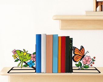 May include: A pair of black metal bookends featuring colorful designs. The left bookend displays a green moth with pink, yellow, and blue flowers. The right bookend features an orange monarch butterfly with pink flowers and green leaves.