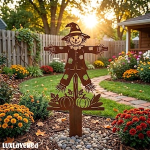 May include: A brown metal garden stake featuring a cutout scarecrow wearing a hat and patched clothing, standing above two pumpkins and autumn leaves. The design includes the text "luxlayered" at the bottom left corner of the image.