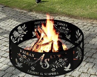 May include: A black metal fire pit with a floral and bird design, and the names "Adam & Sophia" are cut out. The fire pit is filled with burning wood and flames. The word "FAMILY" is also cut out.