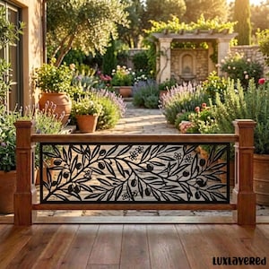 May include: A wooden railing featuring a black metal insert with a laser-cut design of olive branches, leaves, and small flowers. The railing is constructed with two vertical wooden posts and a horizontal wooden frame, set against a garden.