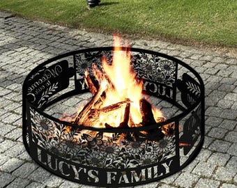May include: A black, circular fire pit with a floral and leaf design cut into the metal. The words "LUCY'S FAMILY" are displayed on the front. The fire pit contains a burning fire with orange and yellow flames.