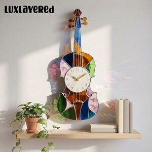 May include: A violin-shaped wall clock crafted from multi-colored stained glass panels in shades of blue, green, amber, and pink. The clock features a circular white face with black numerals and gold-toned hands, mounted on a wall.
