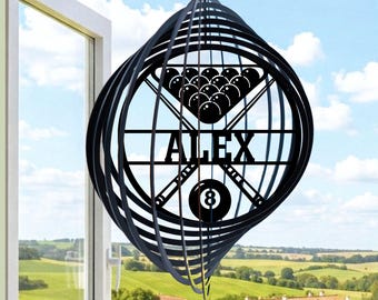May include: Black metal wind spinner with a pool table design. The spinner features a triangle of billiard balls, crossed cues, and the name "ALEX". The number 8 ball is at the bottom. The text "LUXLAYERED" is at the top left.