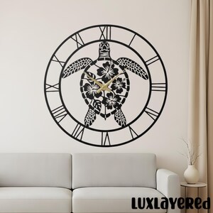May include: A black metal wall clock featuring a sea turtle design. The turtle's shell is adorned with floral patterns, and the clock hands are gold. Roman numerals mark the hours around the clock's perimeter. The clock is mounted on a white wall.