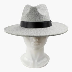May include: A light gray felt fedora hat featuring a wide, flat brim and a structured crown. The hat is accented with a smooth, solid black band encircling the base of the crown, which is secured by a small, circular silver-toned metal stud.