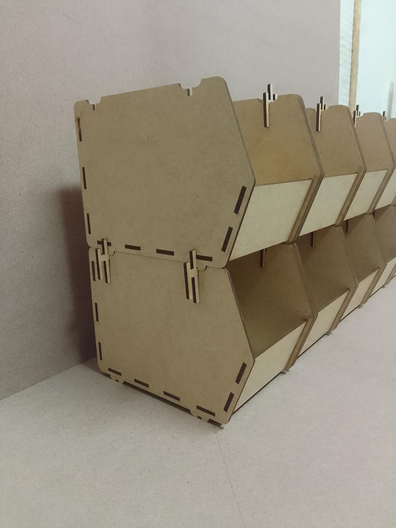 K&ouml;nnte beinhalten: Gestapelte, hellbraune Holz-Aufbewahrungsboxen. Jede Box hat eine trapezf&ouml;rmige Form mit rechteckiger &Ouml;ffnung und hellem Innenpaneel. Die Boxen sind zum Ineinandergreifen konzipiert und eignen sich zur Organisation kleiner Gegenst&auml;nde.