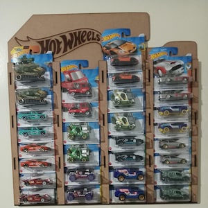 May include: A cardboard display case filled with Hot Wheels toy cars. The display features multiple rows of packaged cars in various colors, including red, green, and blue. The Hot Wheels logo is visible at the top.