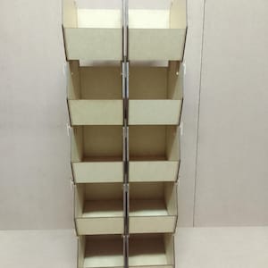 May include: A tall, wooden display stand with multiple rectangular shelves. The stand is constructed from light-colored wood and features a series of open compartments, ideal for showcasing products. The design is simple and functional, suitable for retail or home use.