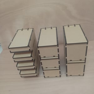 以下が含まれることがあります： 明るい茶色の未完成の木製ボックスが3つ積み重なっています。各ボックスは長方形で、蓋とスロットが付いています。ボックスは明るい茶色の表面に配置されています。収納に最適です。