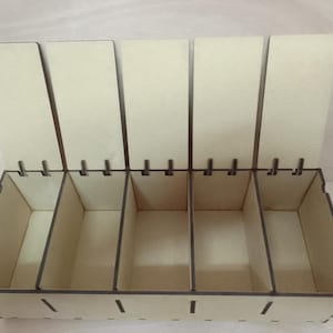 May include: A wooden storage box with five compartments and hinged lids. The box is made of light-coloured wood with dark brown edges. The lids are open, revealing the empty compartments inside. The box is designed for organising small items.