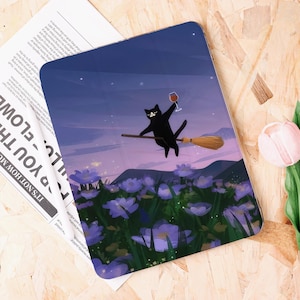 Pode incluir: Capa decorativa para tablet com um gato preto numa vassoura, segurando uma taça de vinho. O gato voa sobre um campo de flores roxas sob um céu estrelado. A capa tem um acabamento brilhante.