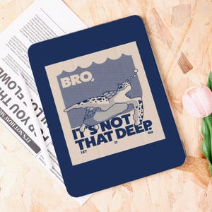 May include: A navy blue rectangular sign featuring a light beige graphic of a swimming sea turtle. The text "BRO. IT'S NOT THAT DEEP. LET IT GO" is printed in navy blue.