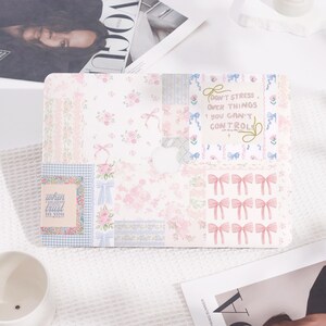 May include: A pink and blue laptop skin with a patchwork design featuring bows, flowers, and the quote "Don't stress over things you can't control".