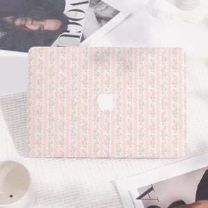 Op de afbeelding: Een roze en witte laptop-skin met een bloemenpatroon. De skin heeft een herhalend patroon van kleine roze bloemen en groene bladeren op een witte achtergrond. De skin is ontworpen om op een laptop te passen.