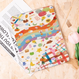 Op de afbeelding: Een kleurrijke tablethoes met een grillig ontwerp met een regenboog, verschillende voedselillustraties en schattige dierfiguren. De hoes heeft een rasterpatroon en een ruitontwerp rechtsonder.
