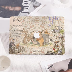 May include: A decorative laptop case featuring a whimsical illustration of Winnie the Pooh and friends. The design includes a floral background and the text "Sometimes the smallest things take up the most room in your heart."