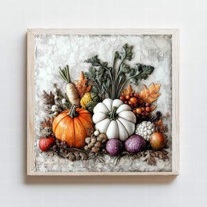 May include: A framed relief sculpture depicting a harvest scene. An orange pumpkin and white pumpkin are surrounded by autumn leaves, grapes, and vegetables. The artwork is set against a textured, off-white background.