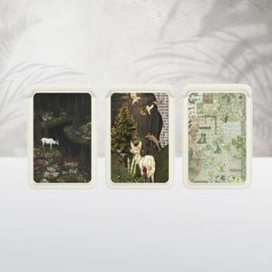May include: Three rectangular decorative trays with nature-themed artwork. The trays feature images of a deer in a forest, a deer with a figure, and a collage of green botanical elements. The trays have a cream-colored border.