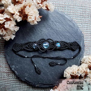 Puede incluir: Pulsera de macramé negra con tres cuentas de piedras preciosas azules iridiscentes. La pulsera tiene lazos ajustables.